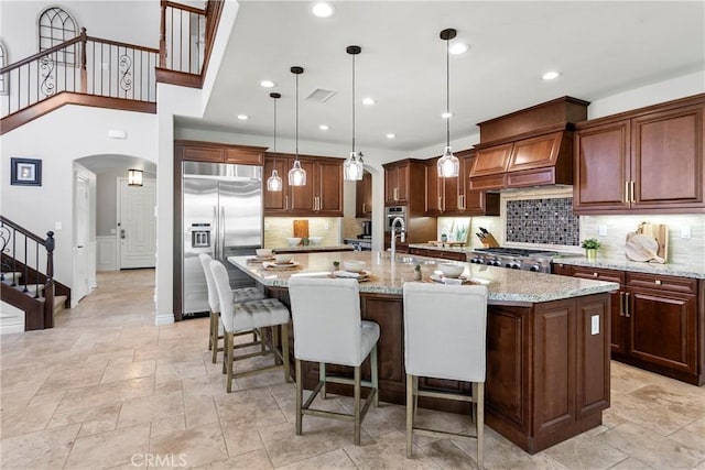 kitchen with arched walkways, appliances with stainless steel finishes, tasteful backsplash, and visible vents