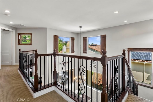 hallway with recessed lighting, an upstairs landing, visible vents, and carpet