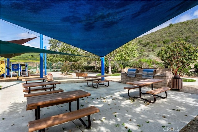 surrounding community with playground community, an outdoor kitchen, and a patio