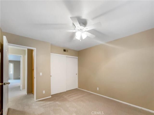 unfurnished bedroom with visible vents, ceiling fan, a closet, baseboards, and light carpet