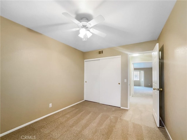 unfurnished bedroom with a closet, light carpet, ceiling fan, baseboards, and visible vents