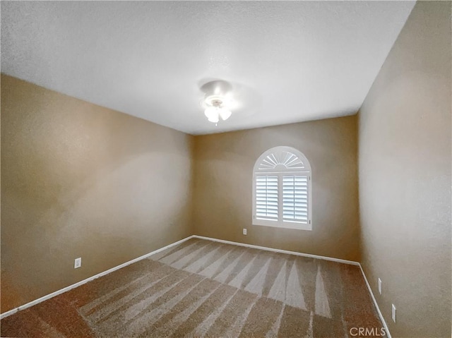 carpeted spare room featuring baseboards
