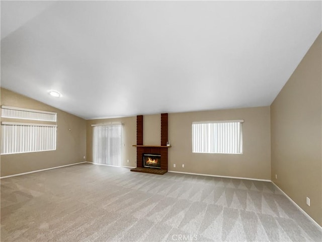 unfurnished living room with baseboards, light carpet, a fireplace, and lofted ceiling