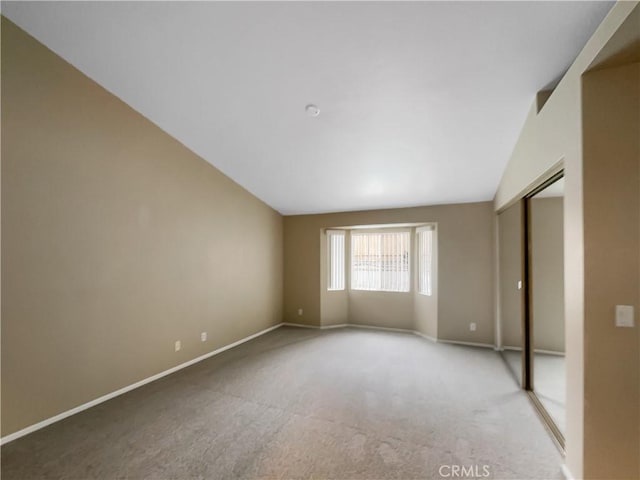 unfurnished bedroom featuring lofted ceiling, carpet, a closet, and baseboards