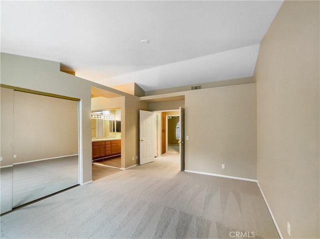 interior space featuring light colored carpet, visible vents, ensuite bathroom, a closet, and baseboards
