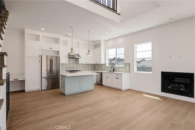 2100 Carnegie Ln, Redondo Beach, CA 90278 - kitchen featuring appliances with stainless steel finishes, a glass covered fireplace, open shelves, white cabinetry, and extractor fan