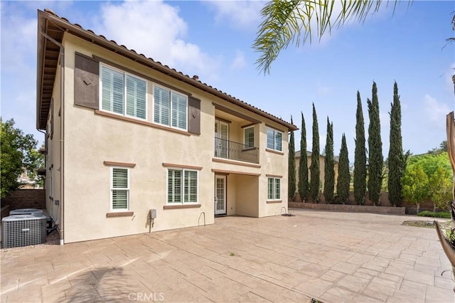 rear view of house with central air condition unit, a patio area, stucco siding, and a balcony