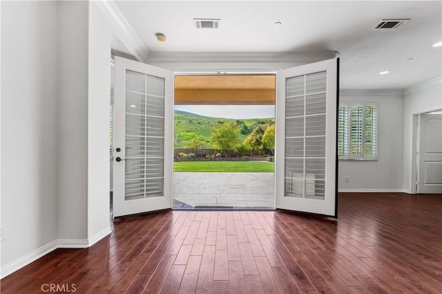 foyer entrance with crown molding, visible vents, baseboards, and wood finished floors