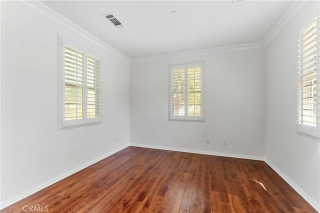 unfurnished room featuring visible vents, baseboards, ornamental molding, and dark wood finished floors