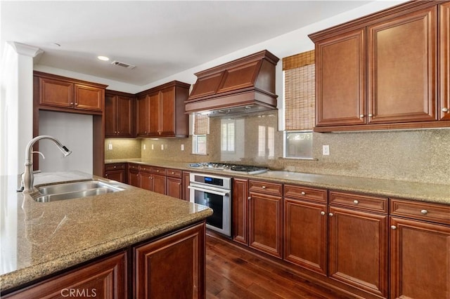 kitchen featuring visible vents, a sink, appliances with stainless steel finishes, dark wood-style floors, and custom range hood
