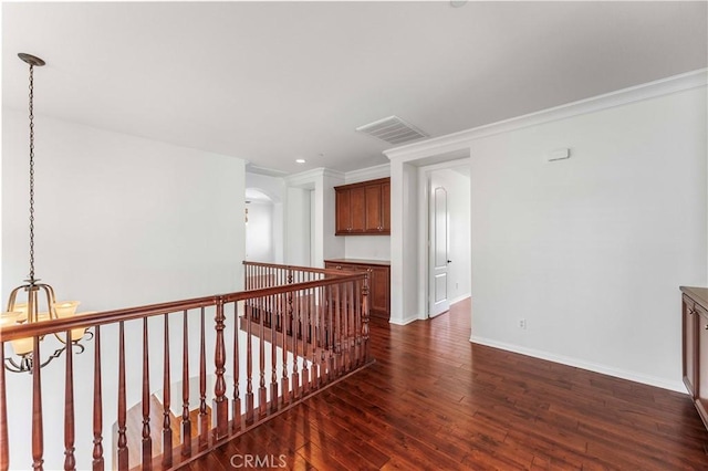 hallway featuring dark wood-type flooring, visible vents, an upstairs landing, baseboards, and a notable chandelier