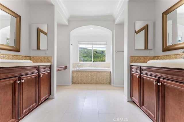 full bathroom featuring a sink, two vanities, crown molding, and a garden tub