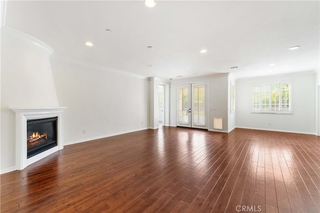 unfurnished living room with baseboards, ornamental molding, dark wood-style floors, recessed lighting, and a glass covered fireplace