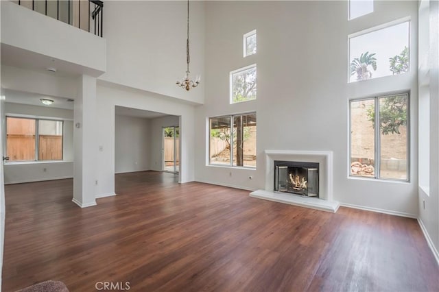 11962 Verona Dr, Fontana, CA 92337 - unfurnished living room featuring a glass covered fireplace, a notable chandelier, baseboards, dark wood-style floors, and a high ceiling