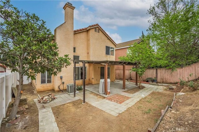 11962 Verona Dr, Fontana, CA 92337 - back of house with stucco siding, a chimney, a pergola, central AC unit, and a fenced backyard