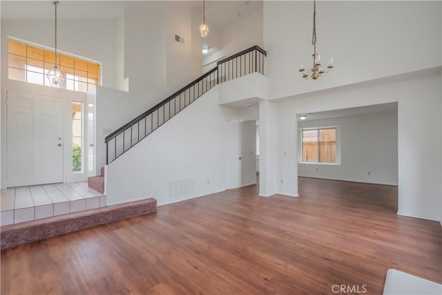 11962 Verona Dr, Fontana, CA 92337 - foyer entrance featuring wood finished floors, an inviting chandelier, a towering ceiling, and visible vents