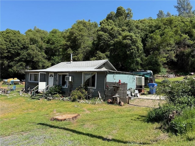 rear view of house featuring a lawn and a wall mounted air conditioner