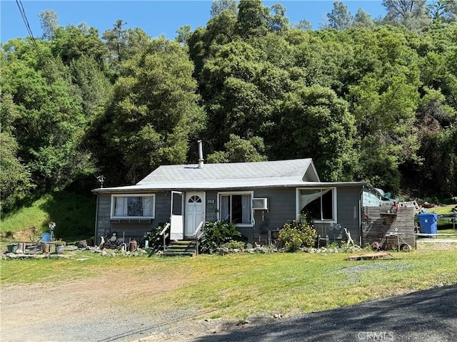view of front of home featuring entry steps, a front lawn, and a wall mounted AC