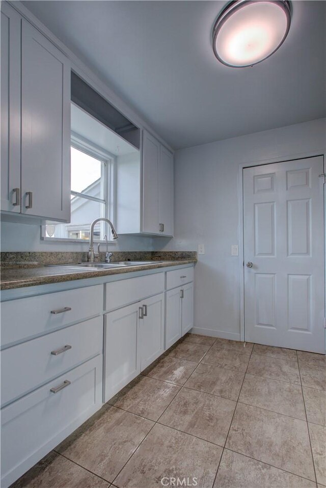1124 S Moffett Rd, Turlock, CA 95380 - kitchen featuring light tile patterned floors, a sink, white cabinets, and dark countertops