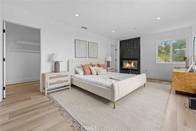 9027 Wonderland Ave, Los Angeles, CA 90046 - bedroom with light wood finished floors, recessed lighting, baseboards, a large fireplace, and a walk in closet