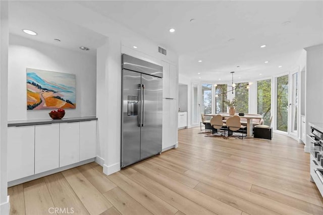 9027 Wonderland Ave, Los Angeles, CA 90046 - kitchen with stainless steel built in fridge, white cabinetry, light wood-style flooring, recessed lighting, and pendant lighting