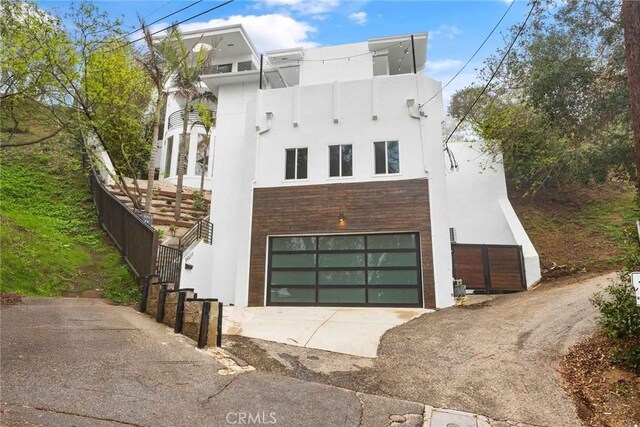 9027 Wonderland Ave, Los Angeles, CA 90046 - modern home with a garage, stucco siding, asphalt driveway, and stairway