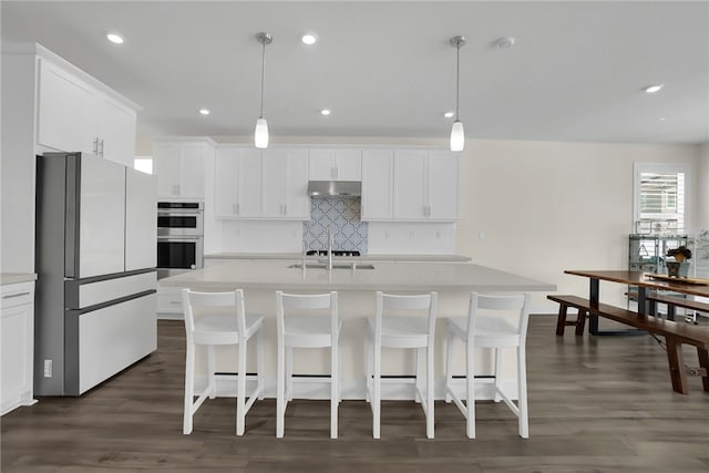 16533 Ground Breaker Ave, Chino, CA 91708 - kitchen with tasteful backsplash, freestanding refrigerator, a kitchen island with sink, under cabinet range hood, and stainless steel double oven