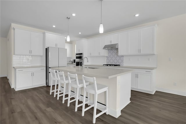 16533 Ground Breaker Ave, Chino, CA 91708 - kitchen with freestanding refrigerator, double oven, dark wood-type flooring, white cabinetry, and under cabinet range hood