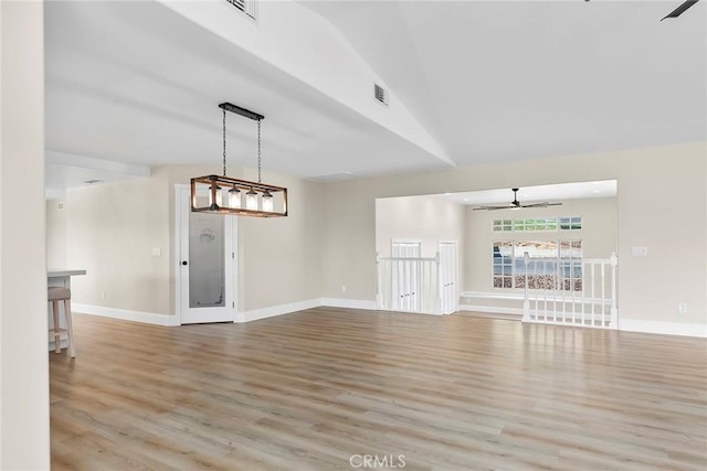 interior space featuring ceiling fan, visible vents, wood finished floors, lofted ceiling, and baseboards