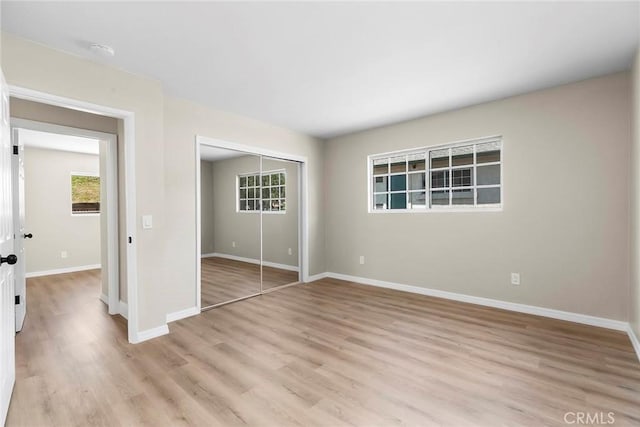 unfurnished bedroom with a closet, baseboards, and light wood-type flooring