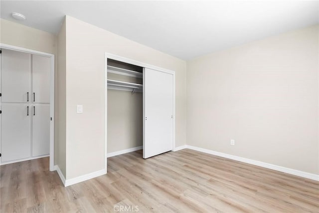 unfurnished bedroom with a closet, light wood finished floors, and baseboards