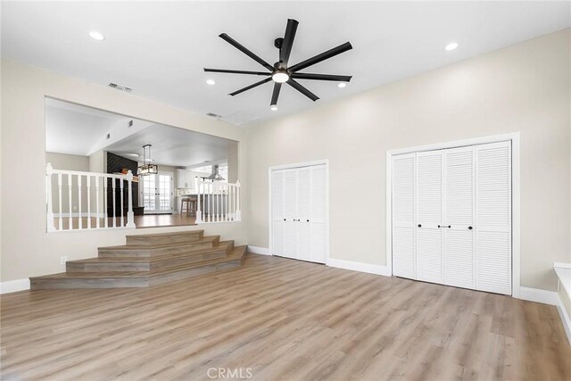 unfurnished living room featuring visible vents, baseboards, recessed lighting, stairway, and wood finished floors