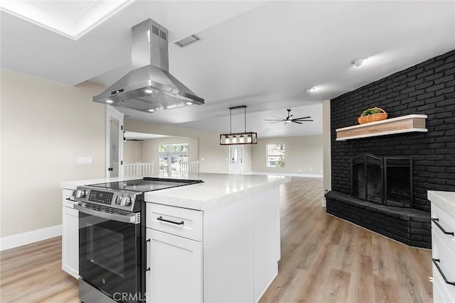 kitchen with open floor plan, stainless steel electric range oven, island exhaust hood, light countertops, and white cabinets