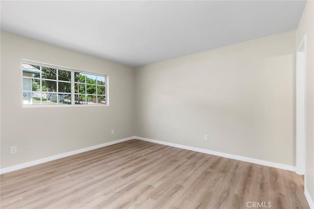 empty room featuring light wood-type flooring and baseboards