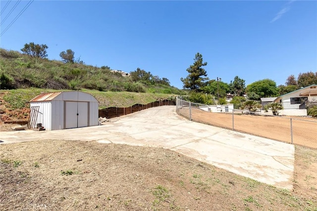 view of yard featuring a storage unit, an outbuilding, and fence