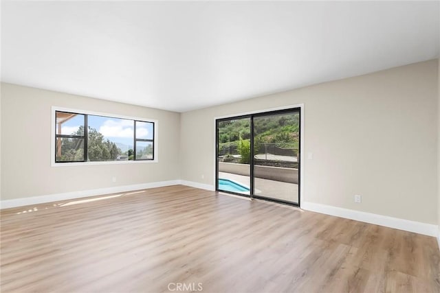 empty room with baseboards and light wood-style floors