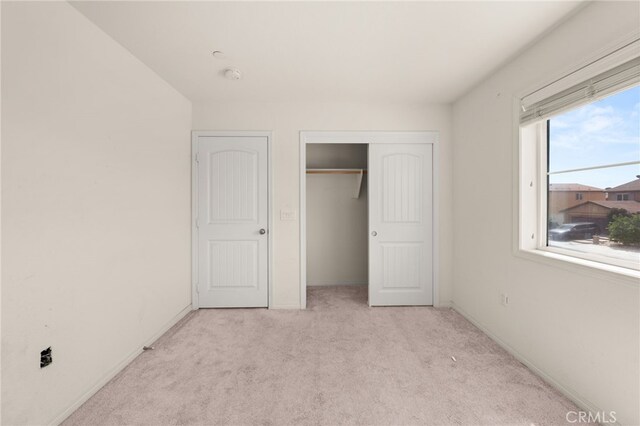 unfurnished bedroom with carpet floors, a closet, and baseboards