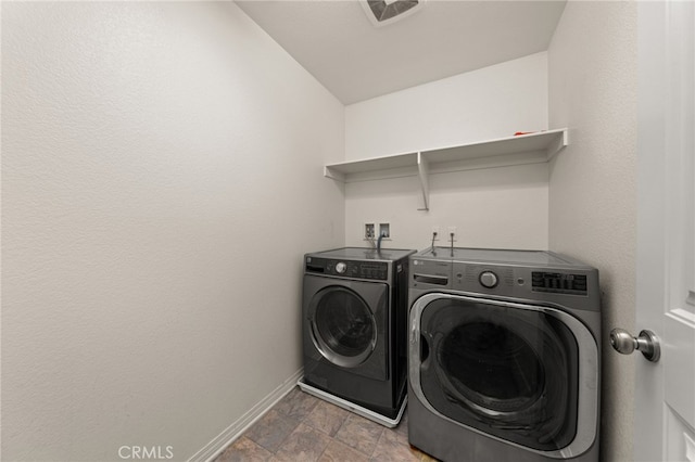 laundry area featuring baseboards, separate washer and dryer, laundry area, and stone finish flooring