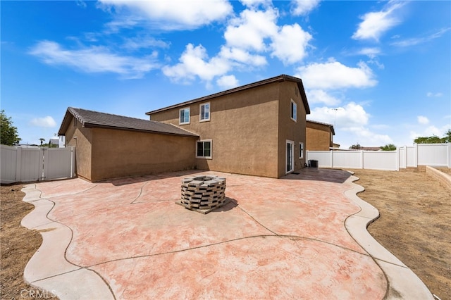 back of house with stucco siding, a fire pit, a patio, and a fenced backyard