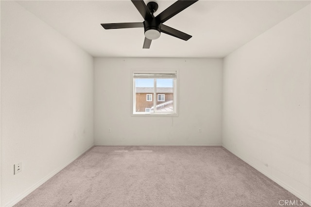 carpeted spare room featuring baseboards and a ceiling fan