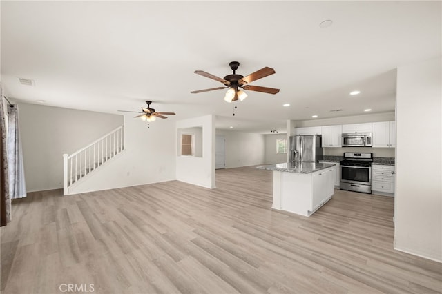 kitchen featuring recessed lighting, open floor plan, white cabinets, appliances with stainless steel finishes, and a kitchen island