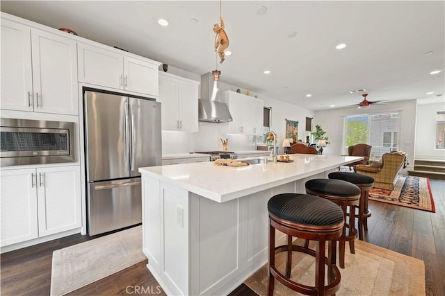 19533 Cardigan Dr, Northridge, CA 91324 - kitchen with wall chimney range hood, a sink, stainless steel appliances, a center island with sink, and a breakfast bar area