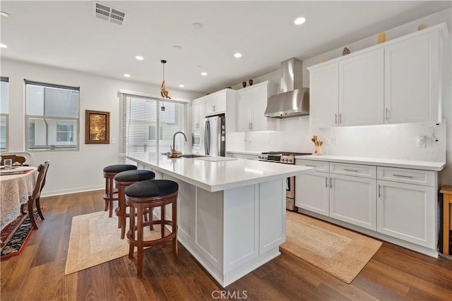 19533 Cardigan Dr, Northridge, CA 91324 - kitchen with visible vents, wall chimney exhaust hood, a kitchen island with sink, dark wood-style floors, and stainless steel appliances