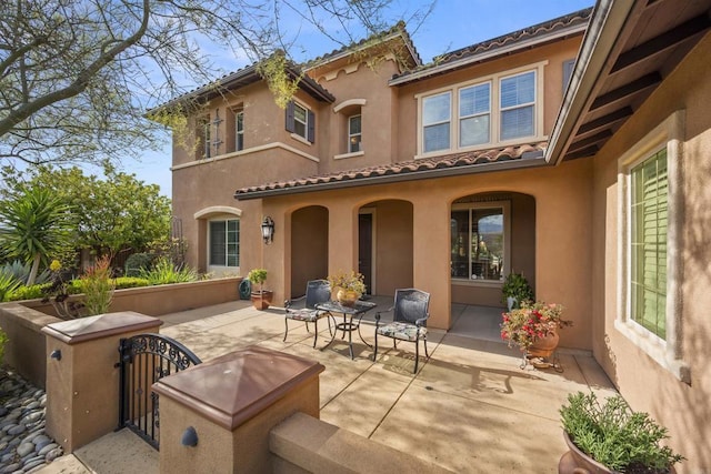 back of house featuring a gate, fence private yard, stucco siding, and a patio area