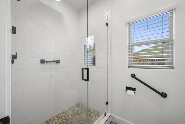 bathroom featuring baseboards, a wealth of natural light, and a stall shower