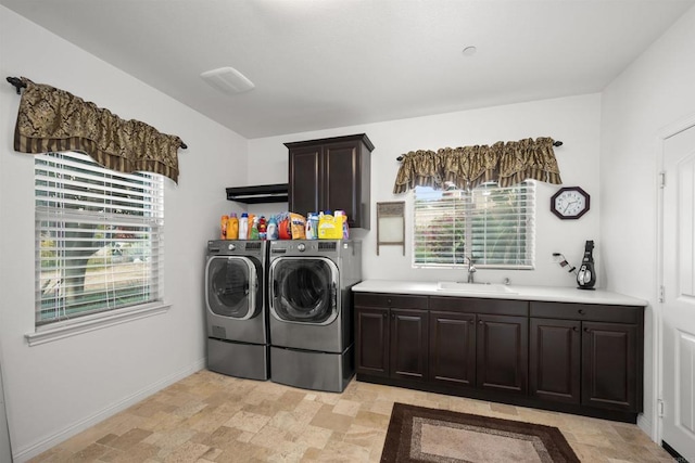 laundry room featuring washer and dryer, cabinet space, a sink, stone finish floor, and a wealth of natural light