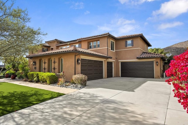 mediterranean / spanish home with a tiled roof, a garage, concrete driveway, an attached garage, and stucco siding