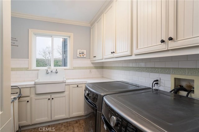 laundry room featuring separate washer and dryer, a sink, ornamental molding, and cabinet space