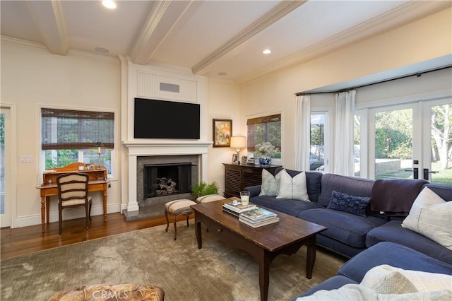 living area featuring beamed ceiling, plenty of natural light, crown molding, and wood finished floors