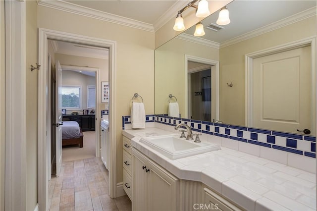 bathroom with vanity, crown molding, backsplash, visible vents, and wood finished floors